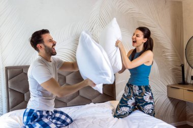 Mutlu genç çift yastık savaşı yaparken eğleniyor..