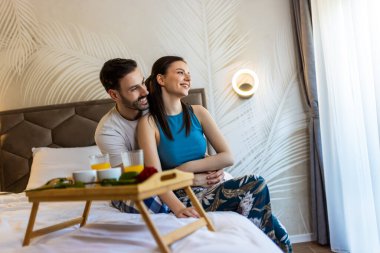 Erkek arkadaşı sevgilisine sarılıyor, pijamalarıyla pencereden içeri bakıyorlar..