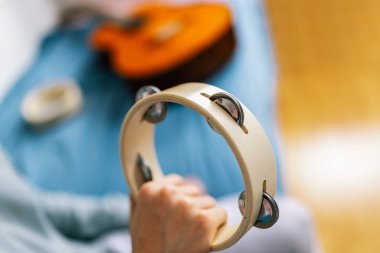 Genç bir çocuk yatağında otururken enerji ve coşkuyla tef çalıyor, rahat odasına ritim ve hayat getiriyor..