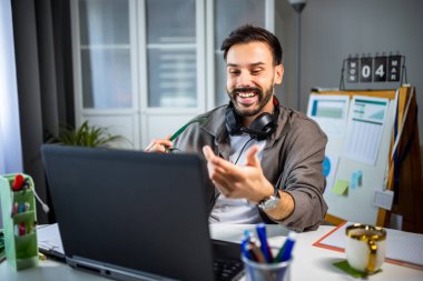 Boynunda kulaklıkla evden çalışan genç bir adam..
