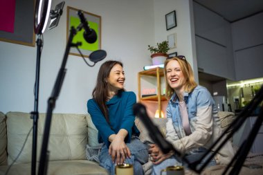 Dairelerinde podcast kaydeden iki genç kadın işbirliği ve yaratıcılık sergiliyor..