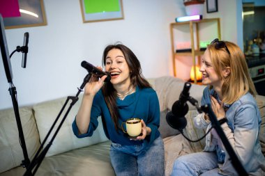 Dairelerinde podcast kaydeden iki genç kadın işbirliği ve yaratıcılık sergiliyor..