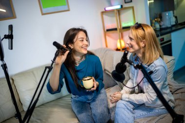 Dairelerinde podcast kaydeden iki genç kadın işbirliği ve yaratıcılık sergiliyor..