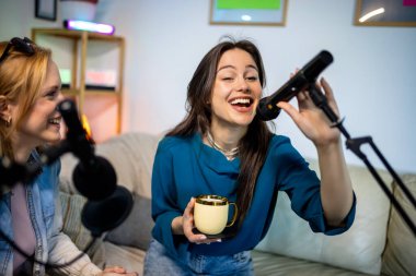 Dairelerinde podcast kaydeden iki genç kadın işbirliği ve yaratıcılık sergiliyor..