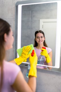 Banyo aynasını temizleme: kadın leke çıkarmak için bez kullanıyor.