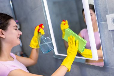 Banyo aynasını temizleme: kadın leke çıkarmak için bez kullanıyor.