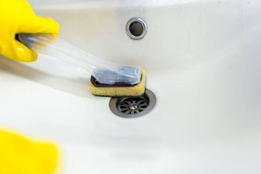 Temizlik için banyo lavabosunu temizleyen elin yakın çekimi..