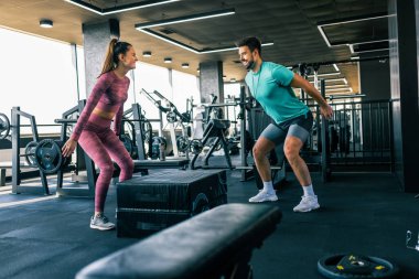 Spor salonunda kişisel antrenörünün rehberliğiyle çalışan bir bayan sporcu..