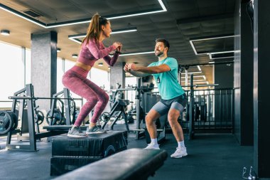 Spor salonunda kişisel antrenörünün rehberliğiyle çalışan bir bayan sporcu..