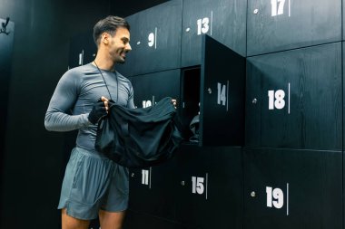 Formdaki adam eşyalarını spor salonunun soyunma odasındaki dolaba koyar..