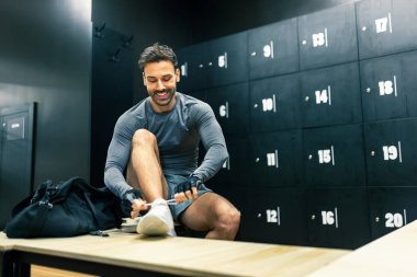 Yakışıklı adam spor salonunun soyunma odasında çalışmaya hazırlanıyor..