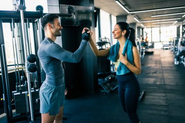 Spor salonunda iyi bir antrenmandan sonra iki fit insan beşlik çakar..