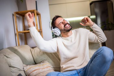 Kulaklıkla müzik dinleyen genç bir adam evde dinleniyor..