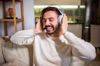 Kulaklıkla müzik dinleyen genç bir adam evde dinleniyor..