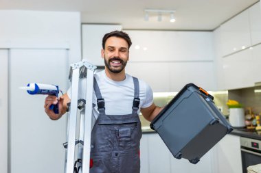 Genç bir tamirci elinde merdiven olan bir daireye gelir ve küçük onarımlar yapmaya hazırdır.. 
