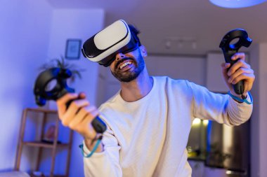 Genç bir adam sanal gerçeklik kulaklığı kullanarak bir video oyunu deneyimine daldı..