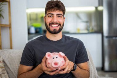 Genç bir adam evinde rahat bir şekilde oturuyor, oyun deneyimine dalmış, elinde bir kumanda, ve ekranın önüne odaklanmış.. 