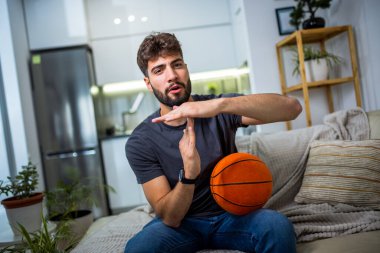 Genç bir adam evinde rahat bir şekilde oturuyor, oyun deneyimine dalmış, elinde bir kumanda, ve ekranın önüne odaklanmış.. 