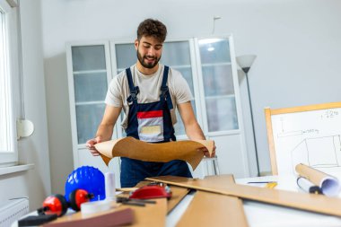 Genç bir adam dairesinin tadilatı için gayretli bir şekilde çalışıyor, lamine döşeme döşemesine odaklanıyor. Elindeki doğru araçlarla, dikkatle ölçer ve plastik panelleri yerine yerleştirir, boşluğu DIY becerileriyle dönüştürür. 