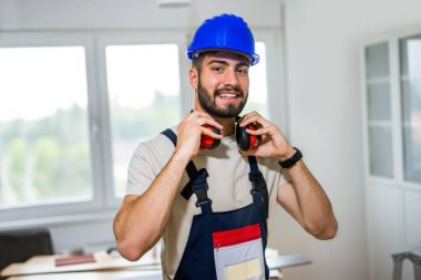 Dairesini yenilemek için özenle çalışan genç bir adamın portresi, lamine döşeme montajına odaklanıyor. Elindeki doğru araçlarla, dikkatlice ölçüyor ve plastik panelleri yerine yerleştiriyor, boşluğu DIY ile dönüştürüyor. 