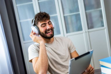Genç öğrenci kulaklık takarken bir tablet kullanarak çalışmalarına daldı. İster konferans dinlesin, ister eğitim videoları izlesin, ister çevrimiçi araştırmalara odaklansın, o tamamen dijital öğrenme deneyimiyle meşgul..