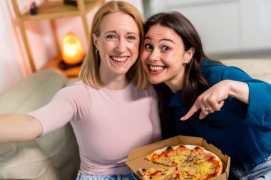 Sıcak bir yuva ortamında, biri hasta ve dinlenirken, diğeri dijital tablet tutarken, en iyi iki arkadaş yan yana oturur., 