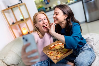 Sıcak bir yuva ortamında, biri hasta ve dinlenirken, diğeri dijital tablet tutarken, en iyi iki arkadaş yan yana oturur., 