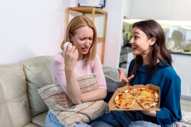 Sıcak bir yuva ortamında, biri hasta ve dinlenirken, diğeri dijital tablet tutarken, en iyi iki arkadaş yan yana oturur., 
