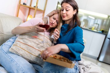 Sıcak bir yuva ortamında, biri hasta ve dinlenirken, diğeri dijital tablet tutarken, en iyi iki arkadaş yan yana oturur., 