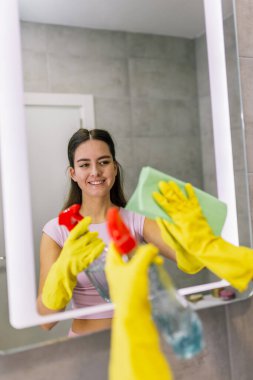 Banyo aynasını temizleme: kadın leke çıkarmak için bez kullanıyor.