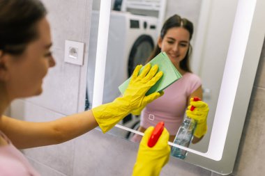 Banyo aynasını temizleme: kadın leke çıkarmak için bez kullanıyor.
