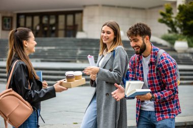 Güneşli bir günde üç üniversite öğrencisi dışarıda birlikte çalışıyor. Bir öğrenci kahve getirdi, çalışma seansına gelişigüzel bir dokunuş ekledi..