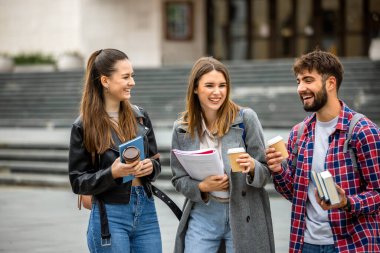 Güneşli bir günde üç üniversite öğrencisi dışarıda birlikte çalışıyor. Bir öğrenci kahve getirdi, çalışma seansına gelişigüzel bir dokunuş ekledi..