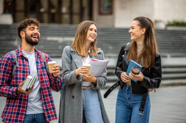 Güneşli bir günde üç üniversite öğrencisi dışarıda birlikte çalışıyor. Bir öğrenci kahve getirdi, çalışma seansına gelişigüzel bir dokunuş ekledi..