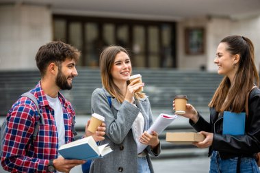 Güneşli bir günde üç üniversite öğrencisi dışarıda birlikte çalışıyor. Bir öğrenci kahve getirdi, çalışma seansına gelişigüzel bir dokunuş ekledi..