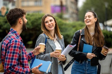 Güneşli bir günde üç üniversite öğrencisi dışarıda birlikte çalışıyor. Bir öğrenci kahve getirdi, çalışma seansına gelişigüzel bir dokunuş ekledi..