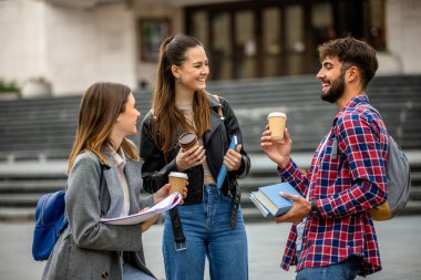 Güneşli bir günde üç üniversite öğrencisi dışarıda birlikte çalışıyor. Bir öğrenci kahve getirdi, çalışma seansına gelişigüzel bir dokunuş ekledi..