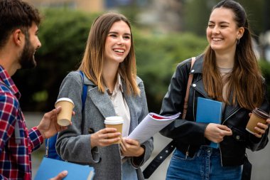 Güneşli bir günde üç üniversite öğrencisi dışarıda birlikte çalışıyor. Bir öğrenci kahve getirdi, çalışma seansına gelişigüzel bir dokunuş ekledi..