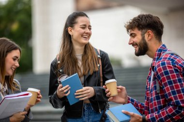Güneşli bir günde üç üniversite öğrencisi dışarıda birlikte çalışıyor. Bir öğrenci kahve getirdi, çalışma seansına gelişigüzel bir dokunuş ekledi..