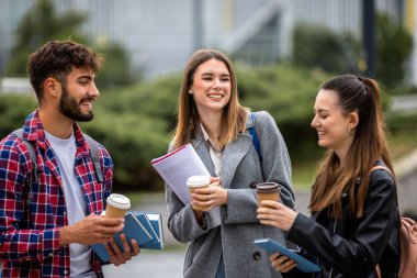 Güneşli bir günde üç üniversite öğrencisi dışarıda birlikte çalışıyor. Bir öğrenci kahve getirdi, çalışma seansına gelişigüzel bir dokunuş ekledi..