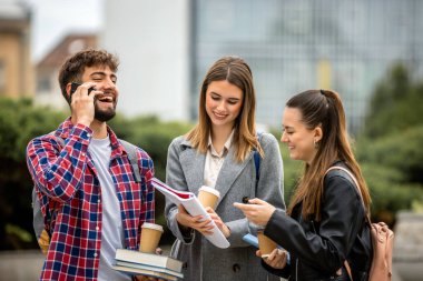 Güneşli bir günde üç üniversite öğrencisi dışarıda birlikte çalışıyor. Bir öğrenci kahve getirdi, çalışma seansına gelişigüzel bir dokunuş ekledi..