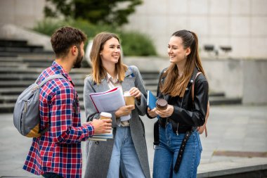Güneşli bir günde üç üniversite öğrencisi dışarıda birlikte çalışıyor. Bir öğrenci kahve getirdi, çalışma seansına gelişigüzel bir dokunuş ekledi..