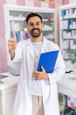 Genç bir eczacı eczanede bir kontrol listesi tutuyor. Profesyonel ortamdaki görevleri dikkatle gözden geçiriyor.