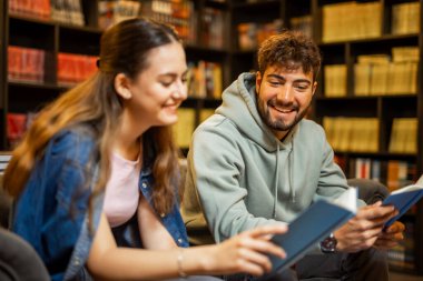 Sessiz bir kütüphanede birlikte çalışan iki odaklı öğrencinin portresi..