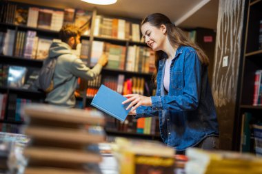 Bayan öğrenci bir kütüphanede kitaplıklara göz atıyor.