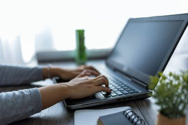 Genç bir Taylandlı kadın evde çalışıyor, rahat bir ofis ortamında bilgisayarına odaklanmış..