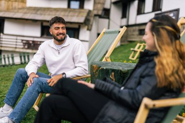 Genç bir çift, manzaralı bir dağ evinde huzurlu bir hafta sonu inzivasının tadını çıkarıyor. Şezlonglarda uzanmış, taze alp havasını emiyorlar..