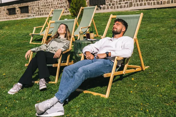 Genç bir adam ve kadın güneşli bir hafta sonu kaçışı sırasında bir dağ otelindeki şezlonglarda dinleniyorlar..