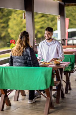 Genç bir çift dışarıda, dağlarda yemek yiyor.
