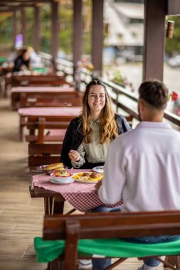 Genç bir çift dışarıda, dağlarda yemek yiyor.